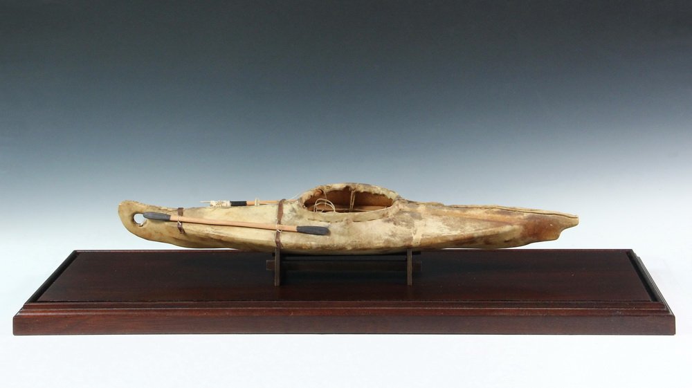 CASED NATIVE MADE KAYAK MODEL - Inuit style, 19th c.,: CASED NATIVE MADE KAYAK MODEL - Inuit style, 19th c., sinew sewn seal skin over cedar wood frame, having paddle and spear, accurately scaled and detailed, sealed with varnish, 21" long, 5 1/4" beam. I