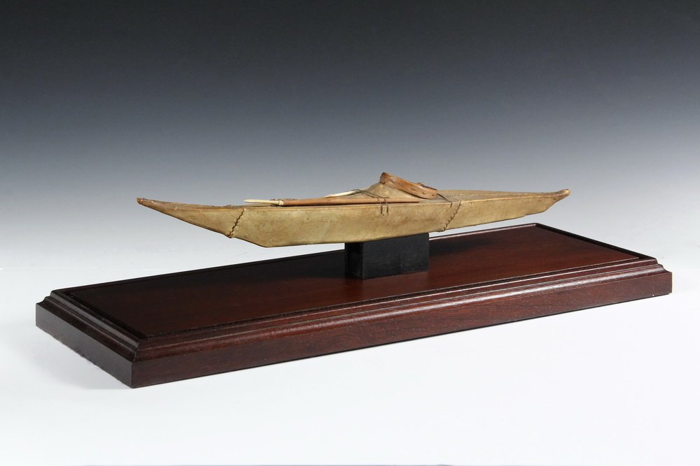NATIVE MADE KAYAK MODEL - Inuit style, 19th c., sinew: NATIVE MADE KAYAK MODEL - Inuit style, 19th c., sinew sewn seal skin over cedar wood frame, having two spears and gaff, accurately scaled and detailed, sealed with varnish, 16" long, 2 1/2" beam. In l
