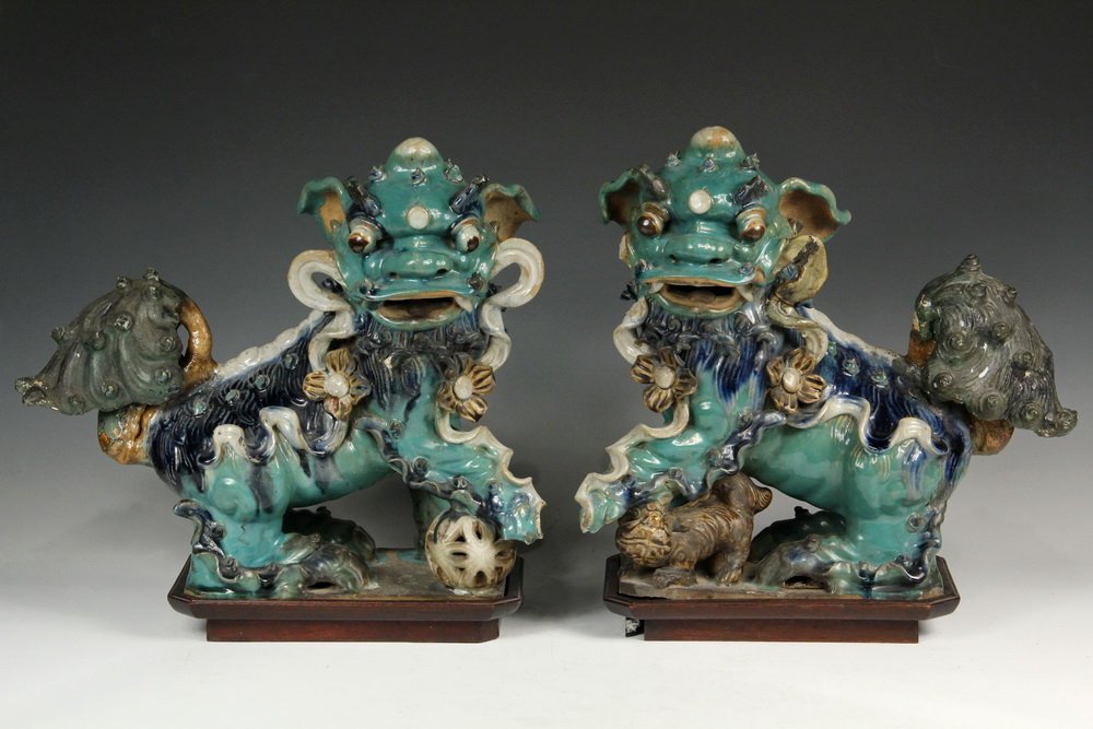 PAIR OF CHINESE ROOF TILE FINIALS - Ming Dynasty Glazed: PAIR OF CHINESE ROOF TILE FINIALS - Ming Dynasty Glazed Stoneware Foo Dog Finials, in opposing stances, with green, blue and brown glazes, on later wooden stands, 15 1/2" x 14" x 18" (figures only). W