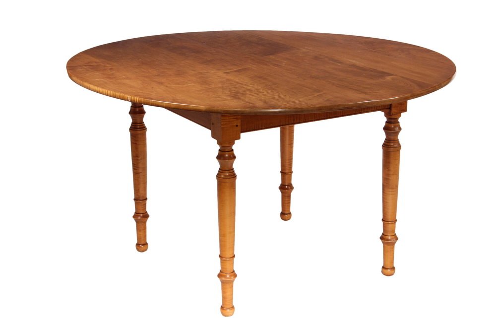 COUNTRY MAPLE DINING TABLE - Tiger Maple Replica by: COUNTRY MAPLE DINING TABLE - Tiger Maple Replica by Leonards (Seekonk, MA), 54" round laminated top with turned and tapered Sheraton style legs. 30" tall. Good condition.