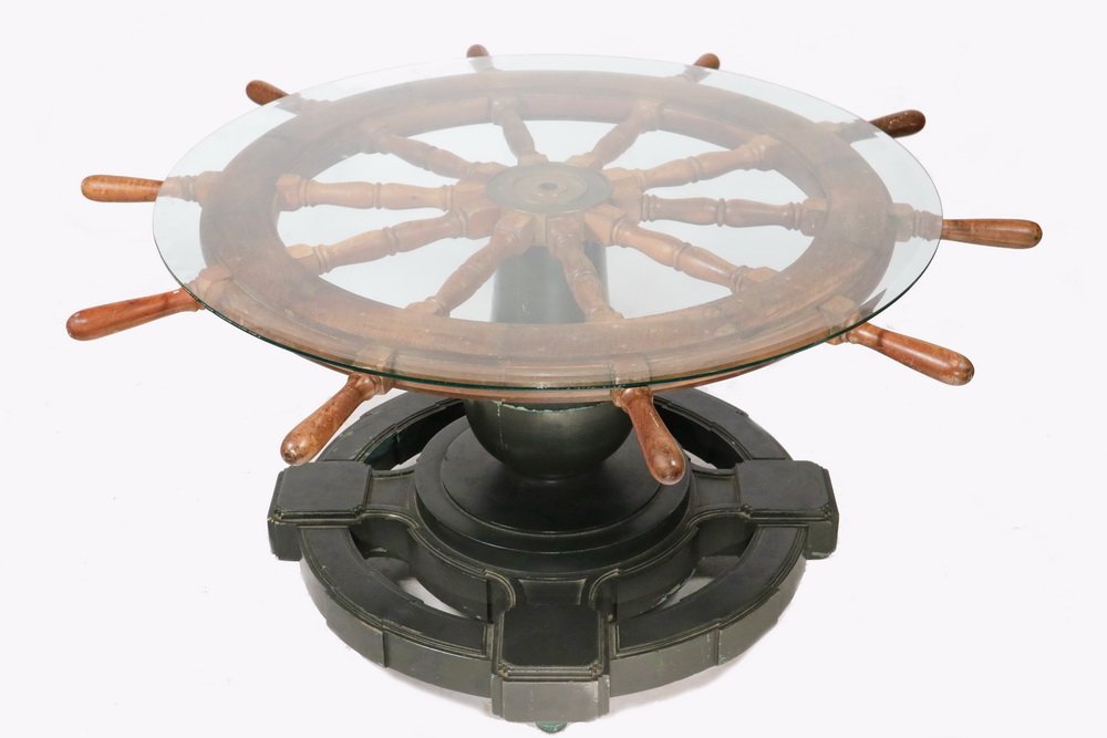NAUTICAL THEMED CENTER TABLE - Round Table made up from: NAUTICAL THEMED CENTER TABLE - Round Table made up from an old Ship's Wheel, with very thick beveled glass top, resting on substantial black enameled base.