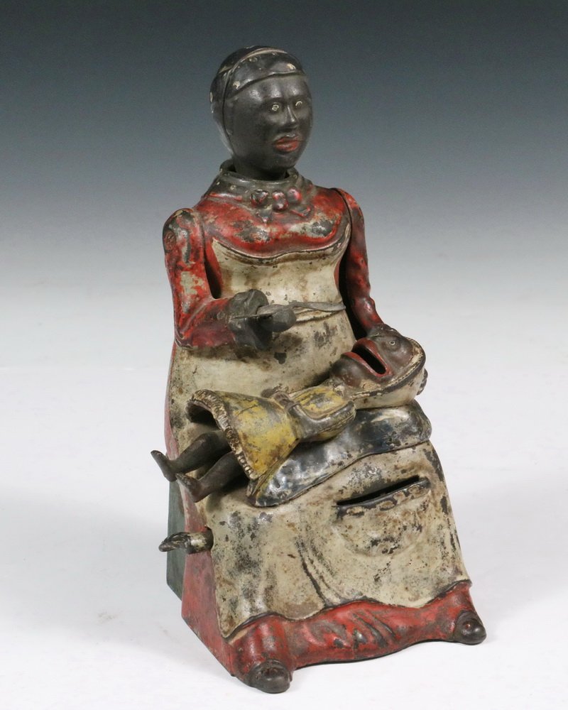 MECHANICAL BANK - Painted Cast Iron "Mammy with Spoon": MECHANICAL BANK - Painted Cast Iron "Mammy with Spoon" Mechanical Bank, red dress on Mammy and yellow dress on baby, by Kyser & Rex, Frankfort, PA, c. 1880, a coin is placed in the child's mouth and t