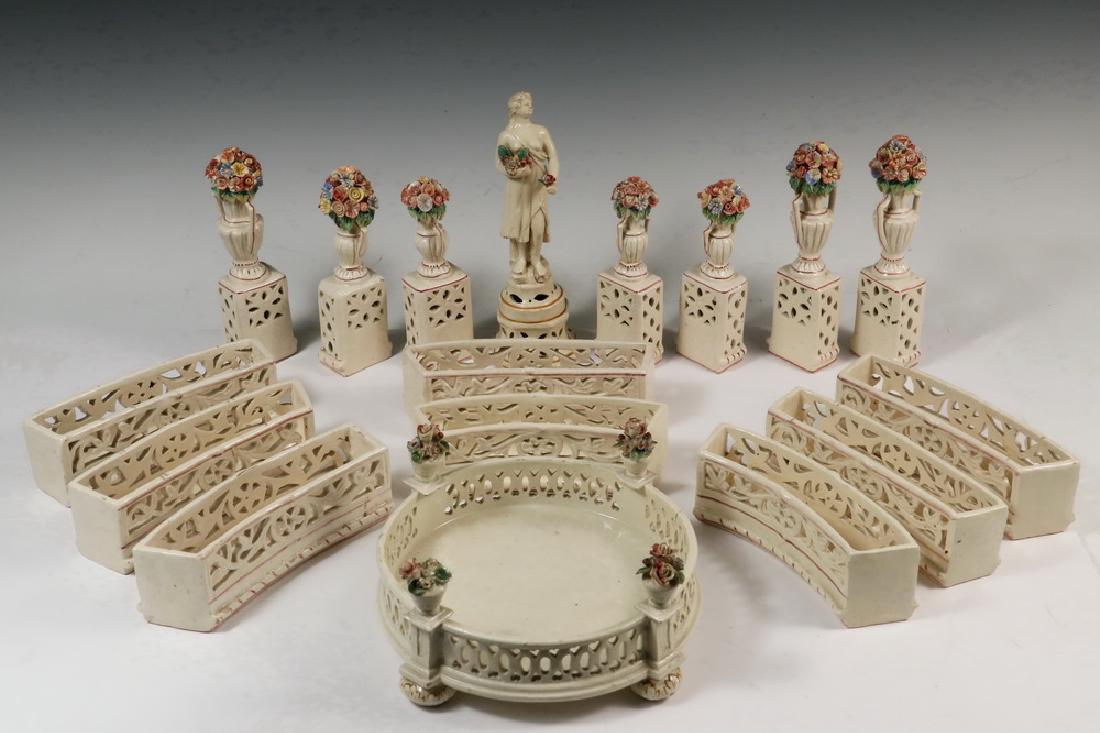 TABLE GARNITURE: Early 20th c Italian (17) Piece Glazed Earthenware Centerpiece Set, each piece numbered, including: a round central platform (7 5/8" diameter, 4 1/4" high), a figure on pedestal (8 1/2" high), (7) urn