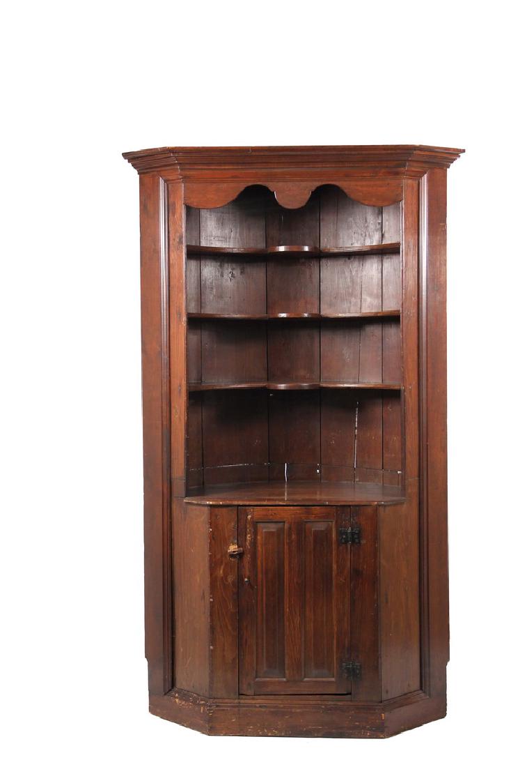 PINE BARREL BACK CORNER CUPBOARD: 18th c. Maine Country Open Cupboard in walnut stained pine, one piece, with a flat molded cornice, canted sides with molded frame, shaped valance above three shaped shelves, bullnose working surface, 