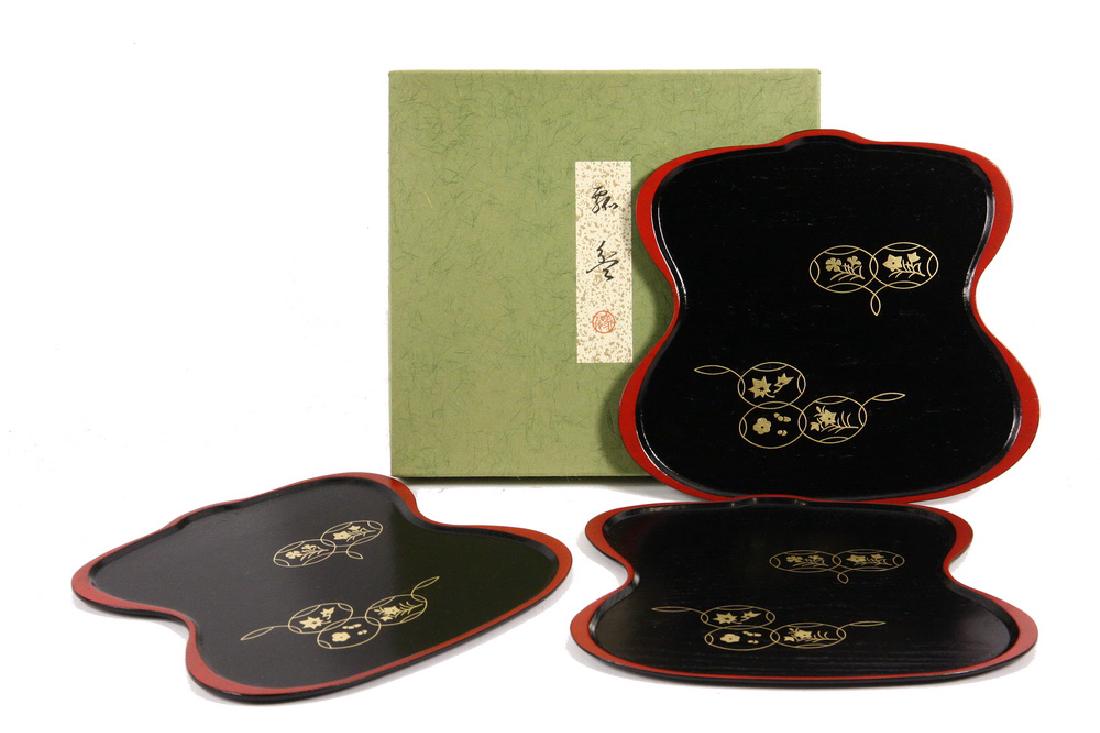 (SET OF 3) JAPANESE LACQUER TRAYS: Place Mat Type Trays in double gourd shape, black with red edges and hir-makie designs. Signed Zohiko, but not their best quality. Nice useful pieces thinly lacquered but with a practical wood grain f
