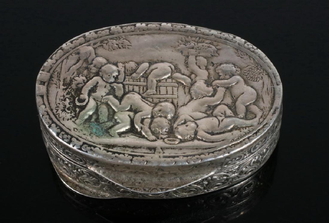 PILL BOX: German 800-Silver Oval Pill Box, late 19th c., with hinged repousse decorated lid with frolicking putti scene, chased sides, 1/2" high, 1 5/8" x 1 1/4", .51 ozt. Wear to lid decoration, slightly missh