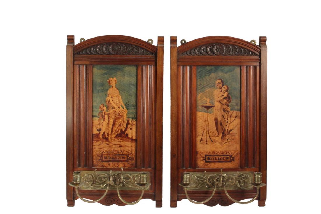 PAIR OF VICTORIAN PICTORIAL CANDLE SCONCES: Late Victorian Two-Arm Brass Candle Sconces with raised rose brass backplate, set onto a large molded mahogany framed plaques with rosette carved arched tops, having tiger maple panels painted with al