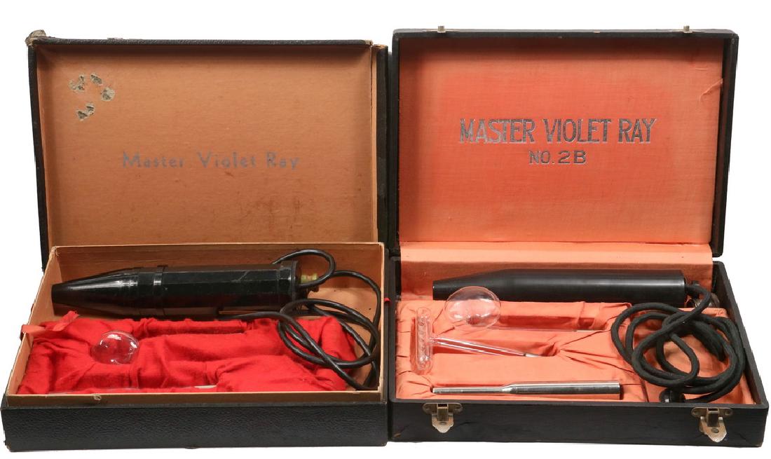 (2) QUACK MEDICINE DEVICES: Circa 1920's, in the original black cases: Master Violet Ray Model 1, in damaged box with lift-off lid, missing the glass 'rake' wand; PLUS Master Violet Ray No. 2B, in hinged case, complete. Both rou