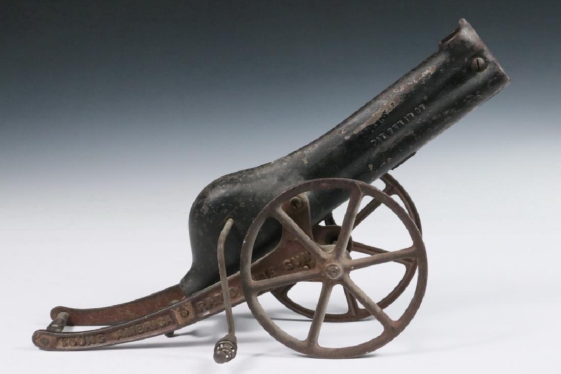 TOY CANNON: Circa 1910 "Young American Rapid Fire Gun' in cast iron and stamped steel, designed to fire marbles, which load at the top of the barrel and are forced out by a crank activated spring. 9 3/4" x 15" x