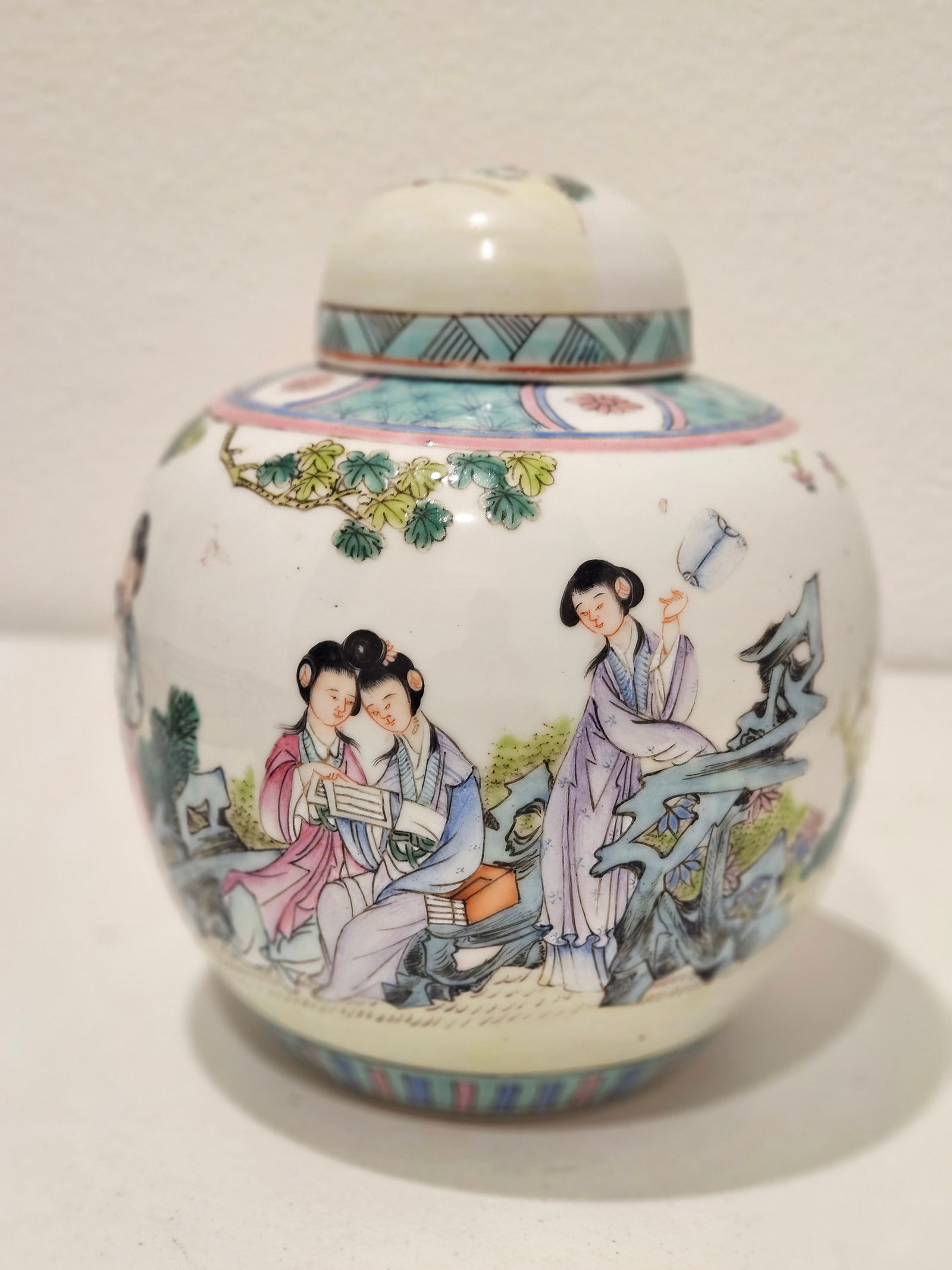 Chinese Antique Famille Rose Ladies at Leisure Tea Caddy from the Late Qing Dynasty: A porcelain tea caddy from the late Qing dynasty, decorated in famille rose enamels with a scene of elegant ladies in a garden or domestic setting.