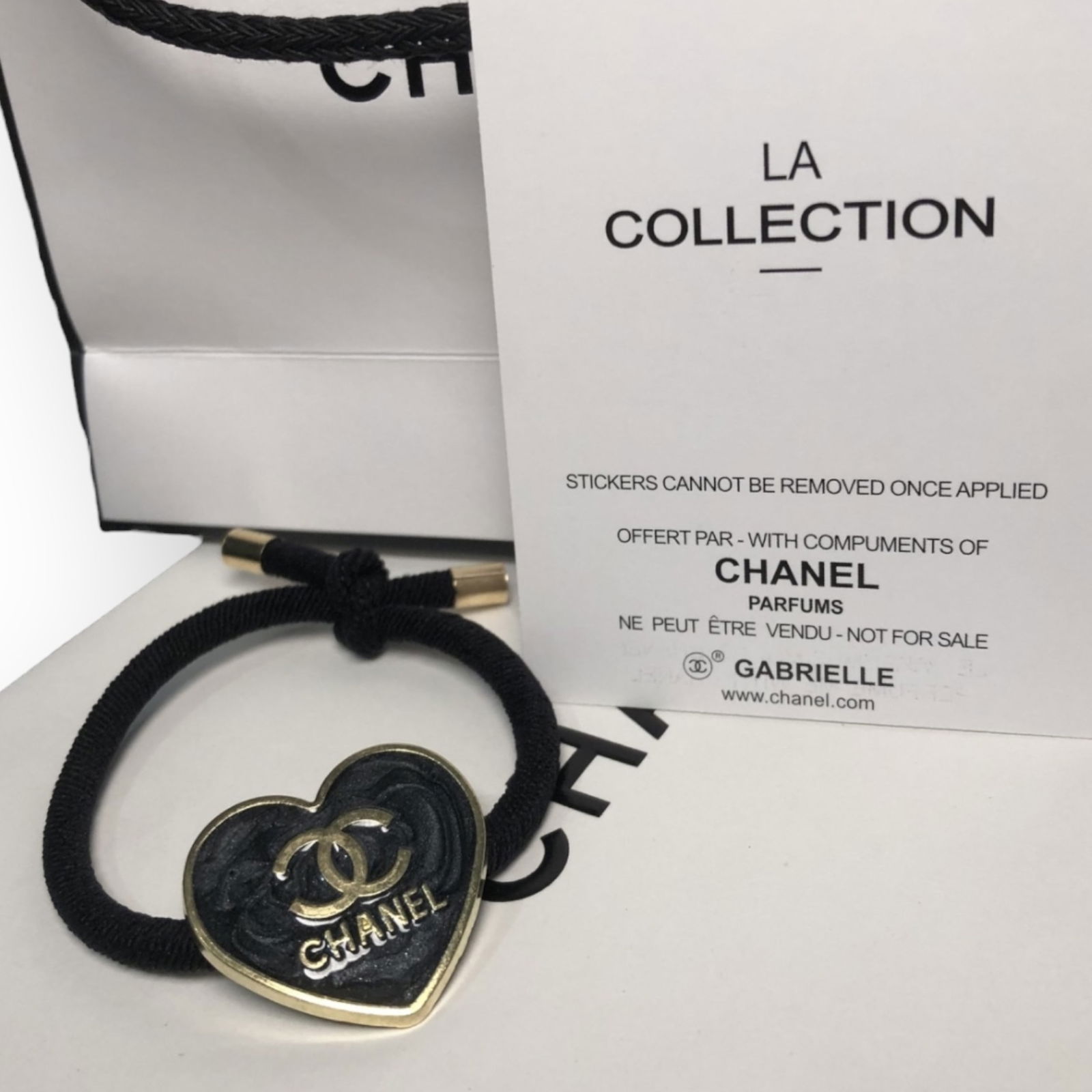 CHANEL Charcoal Grey/Gold Heart Shaped L.A Collection Hair Tie: • CHANEL • Charcoal Grey • L.A Collection • Hair Tie • Heart Shaped • Gold Trim • Front CC/CHANEL Logo • Unopened/In Original Packaging • CHANEL Gift Bag I
