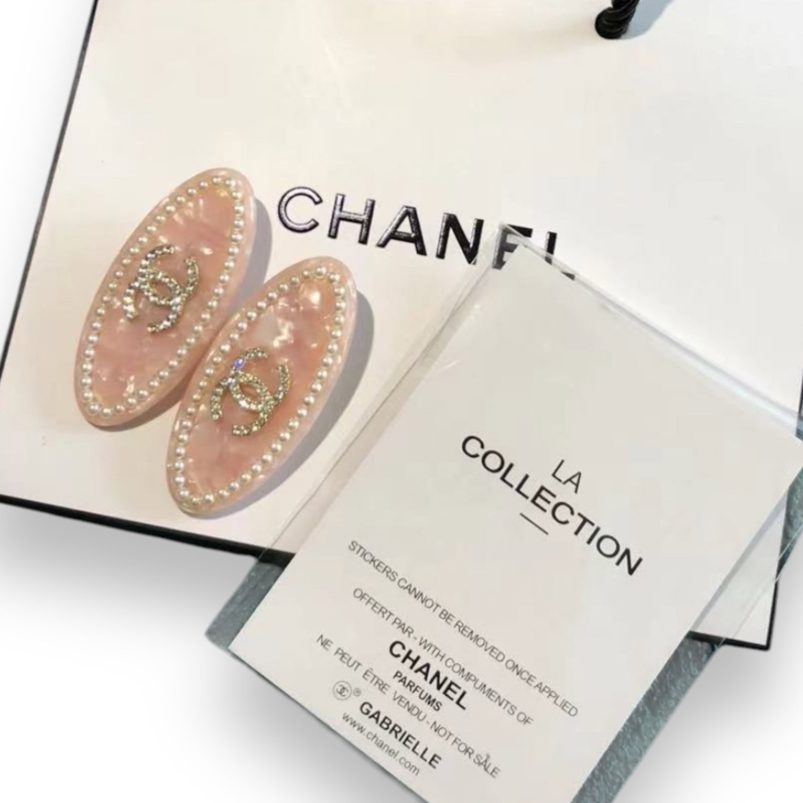 CHANEL 2Pc Baby Pink Pearl/White Rhinestone CC Logo L.A Collection Hair Clips: • CHANEL • Gabrielle • 2Pc Set• Baby Pink Pearl• White Rhinestone Covered CHANEL Logo• White Pearl Trim• Oval Shaped• Silver Tone Hardware• L.A Collection&