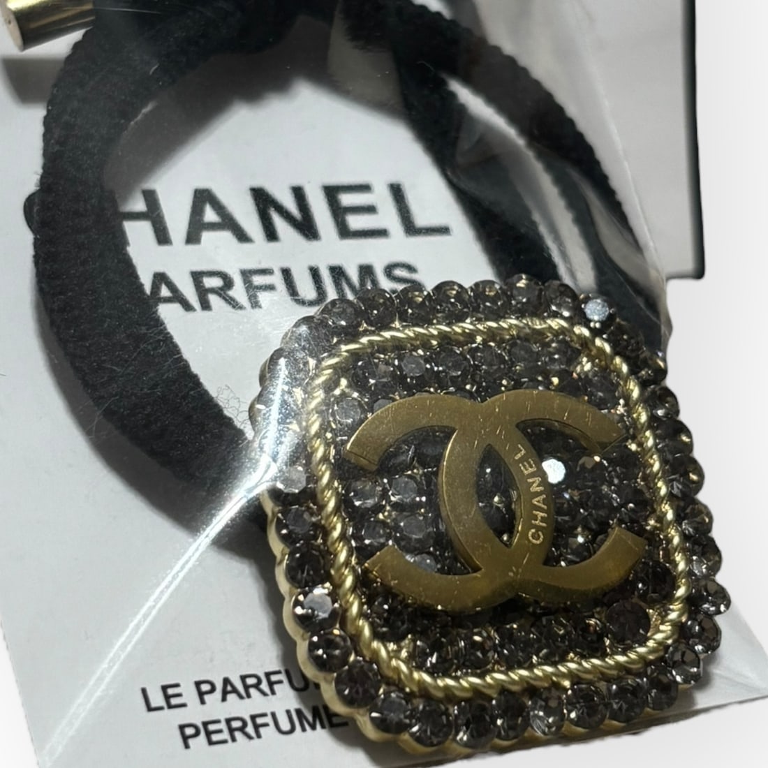 CHANEL Dark Gray/Gold Rhinestone Accented Square CC L.A Collection Hair Tie: • CHANEL • Gabrielle • Dark Grey Accented Rhinestones • Square Shaped • Black Tie • L.A Collection • Hair Tie • Gold CC Logo • Unopened/In Original Packagi