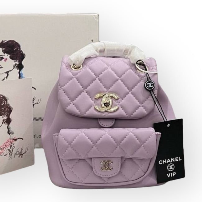 CHANEL Purple/Gold Quilted Mini Duma Beaute Backpack & Original Box: • CHANEL • Pink • Duma Backpack • Quilted Pattern • Front CC Logo Exterior Pocket • Signature CC Twist Lock Closure • Front Exterior Snap Pocket • Adjustable St