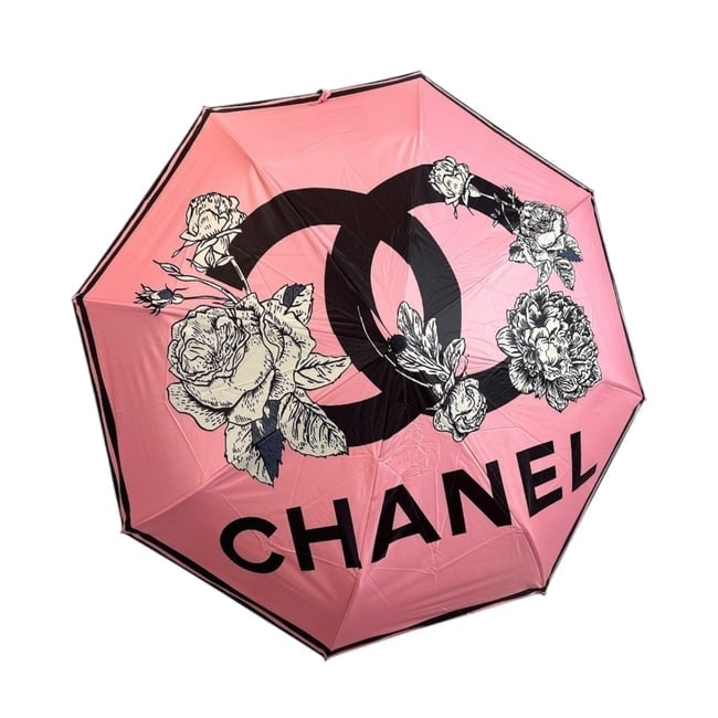 CHANEL Pink/Black Rose Handle Edition Beaute Umbrella, Sleeve, & Original Box: • CHANEL • Umbrella • Pink • Black & White Accents • Original Storage Sleeve Included • Original Box Included • Handle Loop For Easy Carry • Snap Closure •