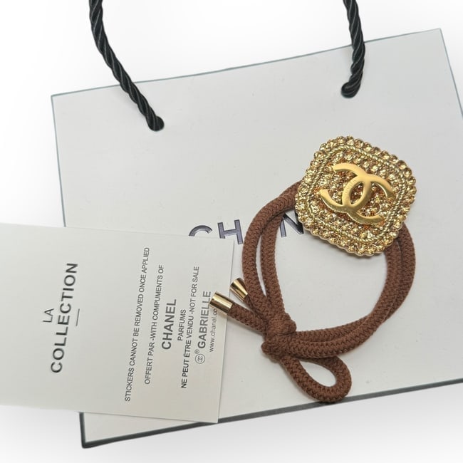 CHANEL Gold/Gold Rhinestone Accented Square CC L.A Collection Hair Tie: • CHANEL • Hair Tie • Gabrielle • Gold Accented Rhinestones • Shape: Square • Tie Color: Brown • L.A Collection • Gold CC Logo • Unopened/In Original Packa