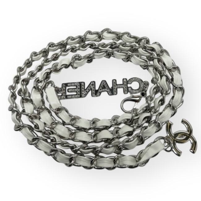 CHANEL Adjustable White/Silver Rhinestone Covered Logo L.A.C Belt: • CHANEL • Belt • White Intertwined Leather Chain • Silver Tone Hardware • Adjustable • Rhinestone Covered CHANEL Logo • Original Gift Bag Included • L.A. Colle
