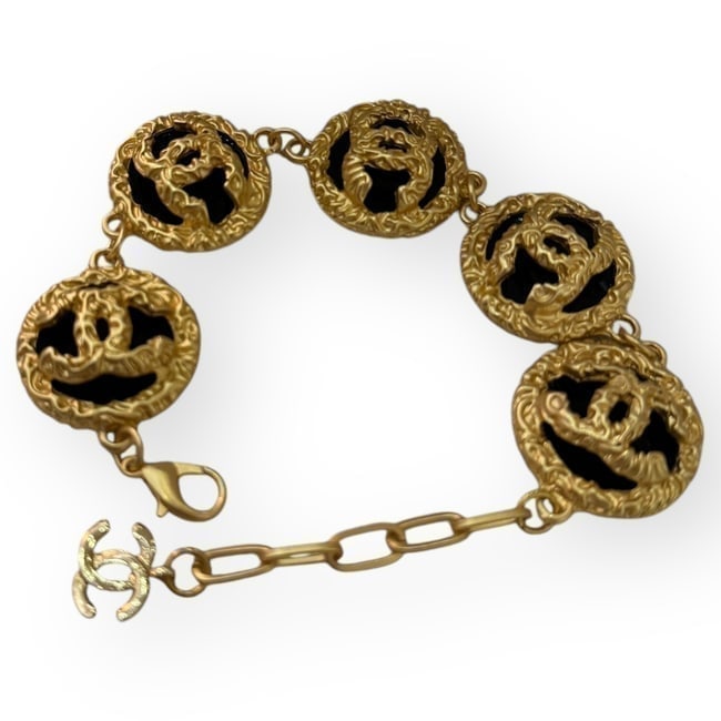 CHANEL Gold/Black Adjustable CC Logo Beaute Bracelet & Original Gift Bag: • CHANEL • Bracelet • Adjustable • Detailed Gold Tone Hardware • Black Accents • 8.7" (in) • CC Logo • Original Gift Bag Included • Makeup/Diffusion