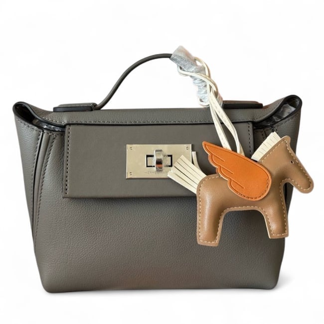 Hermes Grey/Silver 24/24 Evercolor Beaute Bag & Original Box: • Hermes • 24/24 Evercolor • Silver Tone Hardware • Signature Twist Lock Closure • Interior Zip Pocket • Interior Slip Pocket • Original Box Included • Shoulder