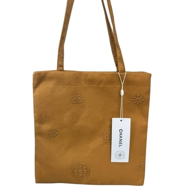 CHANEL Brown Camelia/Logo Decorated U.L Tote: • CHANEL • Tote • Brown • Camelia/Logo Decorated • Canvas • Double Handles • Uniform Line • Snap Closure • 11.8" x 11.4" (in) • Please no