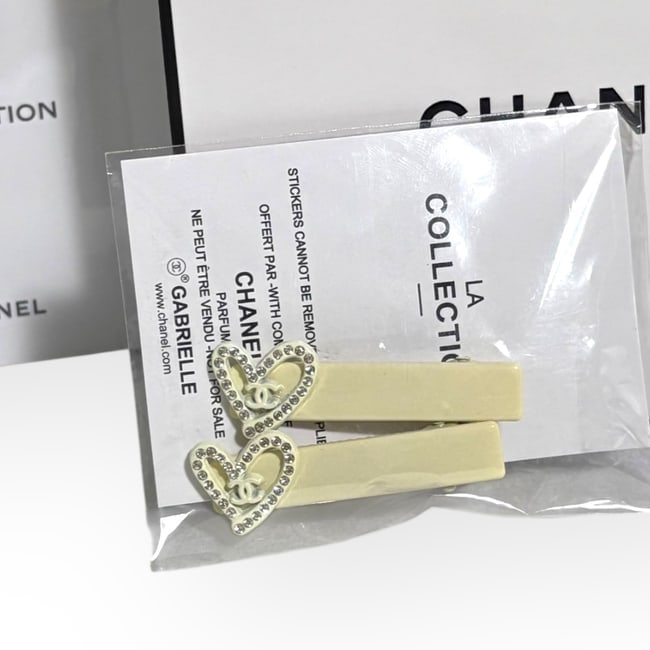 CHANEL 2Pc Set Off White/Rhinestone Heart Hair Clips & Gift Bag: • CHANEL • 2Pc Set • Gabrielle • Off White • Hair Clips • Shape: Rectangle • White Rhinestone Heart Accents • Off White Tone Hardware • L.A Collection