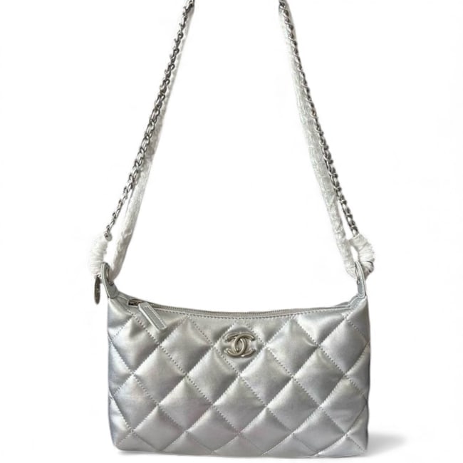 CHANEL Quilted Metallic Silver Hobo Beaute Bag & Original Box: • CHANEL • Hobo Shoulder Bag • Metallic Silver • Quilted Pattern • Silver Tone Hardware • Intertwined Leather Chain Straps • Front Logo • Zip Closure • 10.