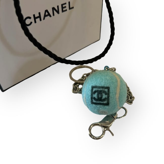 CHANEL Blue/White CC Logo Tennis Ball Beaute Key Chain & Original Gift Bag: • CHANEL • Style: Gabrielle • Collection: L.A. Collection • Type: Keychain • Design: Blue Tennis Ball • Accents: White Accents • Logo: Black CC Logo • Hardware: