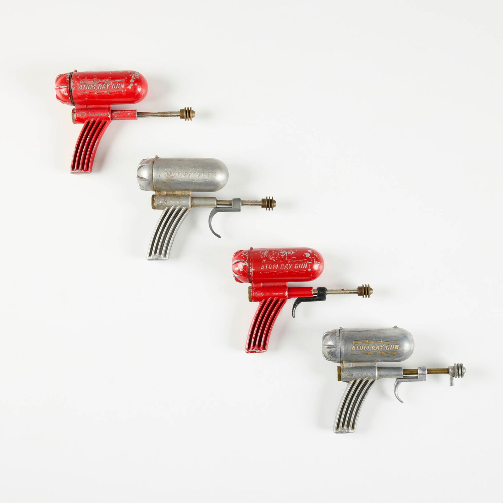 Four Hiller Atom Ray Gun Water Pistols: Four Hiller Atom Ray Gun Water Pistols Hiller Mfg.c. 1948cast aluminum, enameled cast aluminum, brass 4.5 h x 1.5 w x 6.25 d in (11 x 4 x 16 cm) Cast manufacturer's mark to sides of each example 'Hill