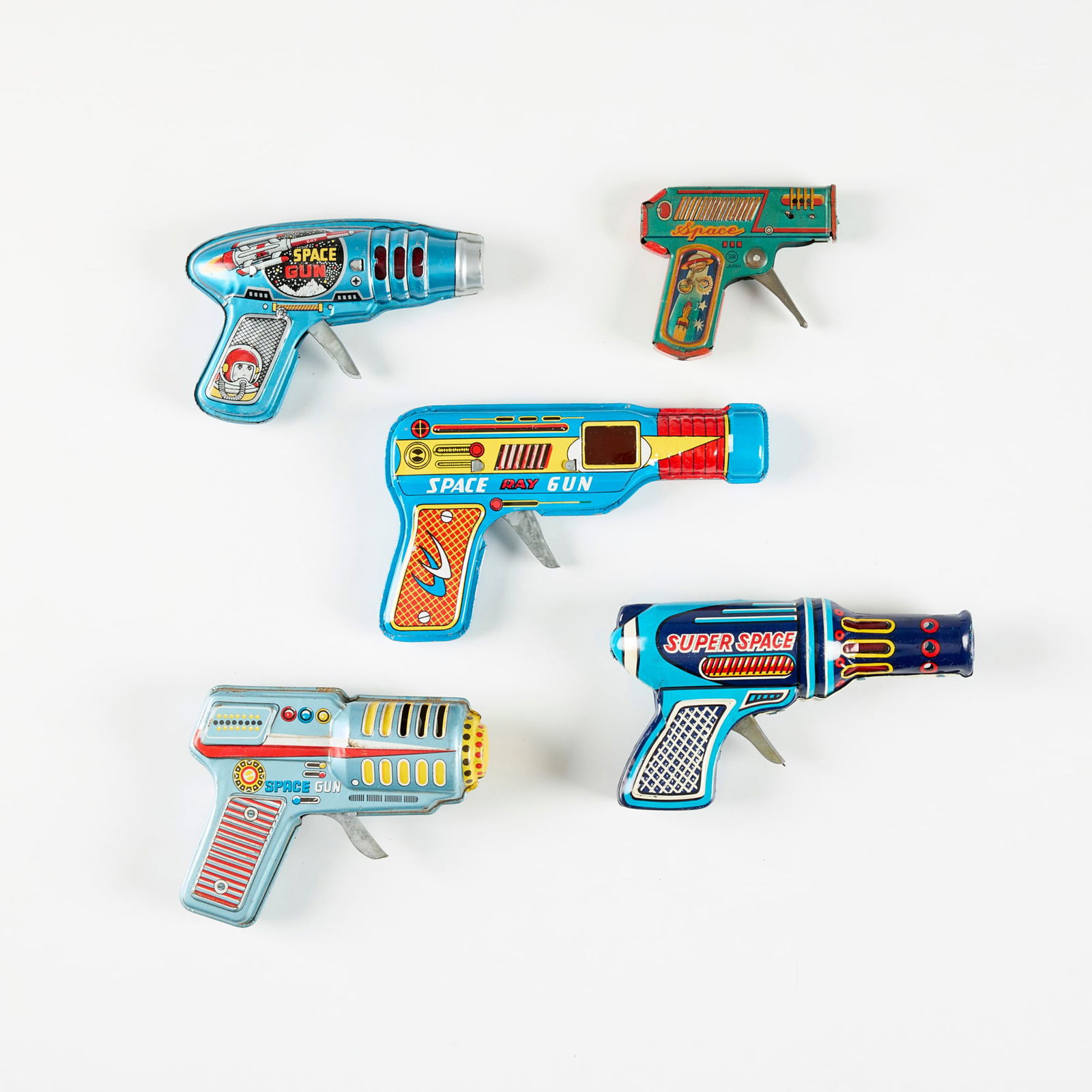 Five Vintage Japanese Tin Ray Guns: Five Vintage Japanese Tin Ray Guns transfer print on metal largest: 4.125 h x 0.875 w x 6.75 d in (10 x 2 x 17 cm) smallest: 3.125 h x 0.5 w x 3.375 d in (8 x 1 x 9 cm) Printed manufacturer's mark to