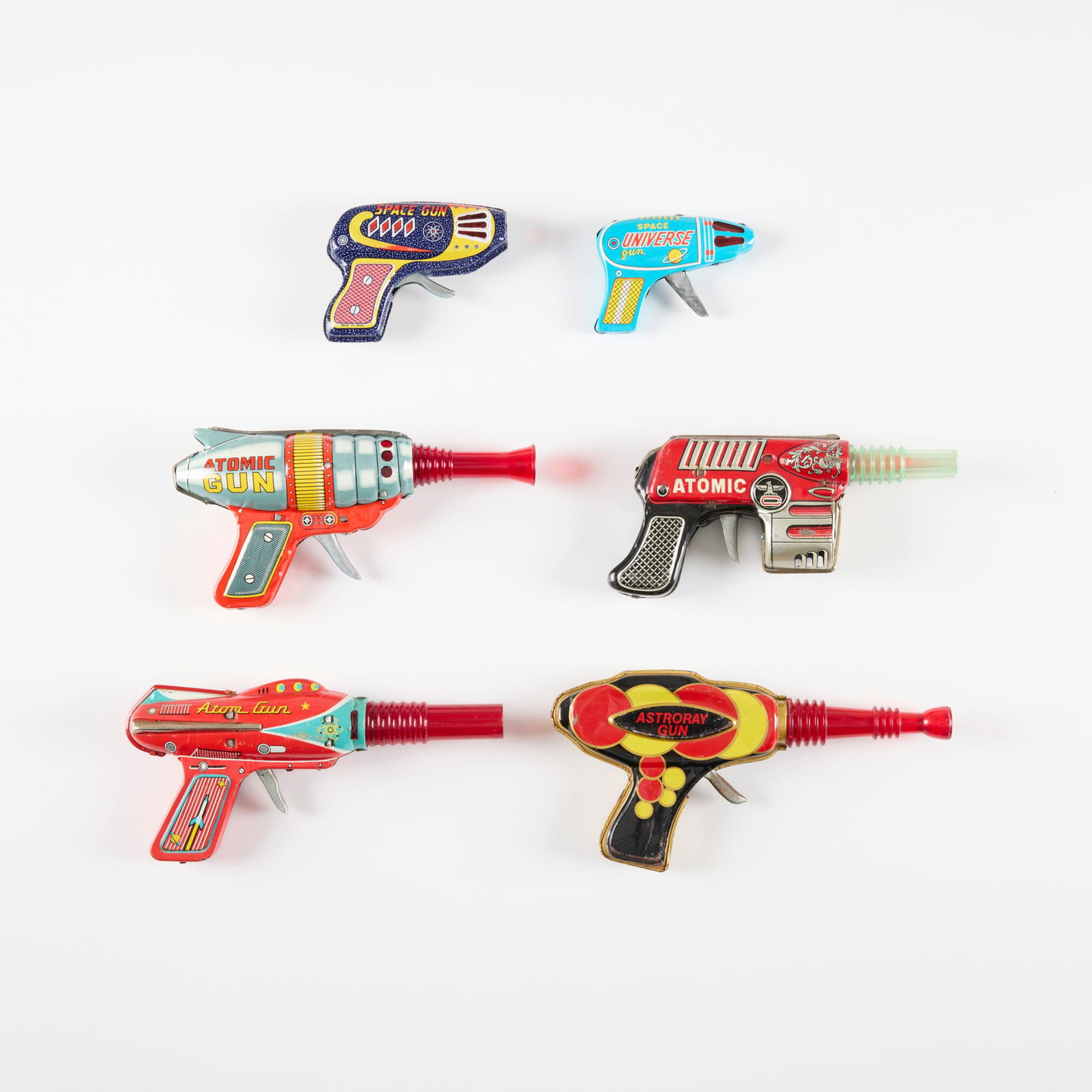 Six Vintage Japanese Tin Ray Guns: Six Vintage Japanese Tin Ray Guns transfer print on metal, molded plastic largest: 4.75 h x 9.5 w x 1.25 d in (12 x 24 x 3 cm) smallest: 3 h x 4 w x 0.875 d in (8 x 10 x 2 cm) Manufacturer's mark to e