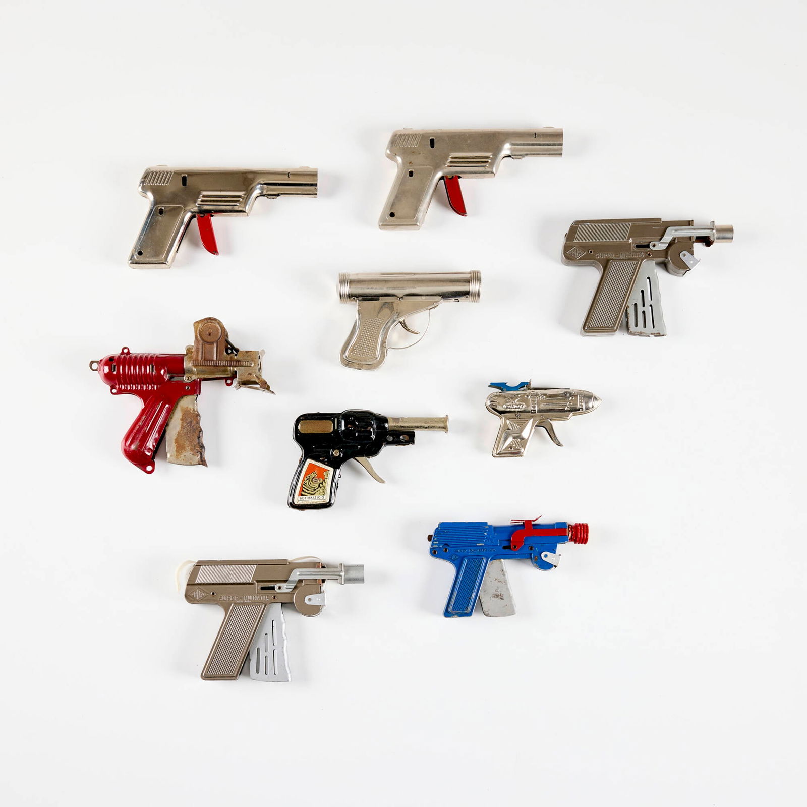 Nine Early American Metal Pop Paper and Click Guns: Nine Early American Metal Pop Paper and Click Guns enameled metal, zinc & chrome-plated steel, molded plastic largest: 4.25 h x 6.375 w x 0.875 d in (11 x 16 x 2 cm) smallest: 2.875 h x 4.25 w x 0.875