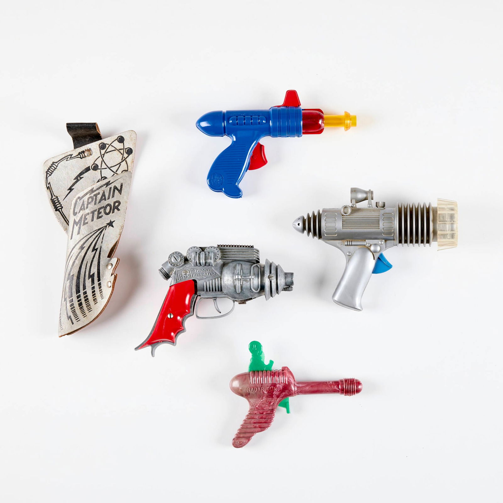 Four Vintage Space Character Ray Guns: Four Vintage Space Character Ray Guns metal, plastic, screen-printed leather largest: 5 h x 7.5 w x 2 d in (13 x 19 x 5 cm) smallest: 5 h x 6.25 w x 1 d in (13 x 16 x 3 cm) Manufacturer's mark to each