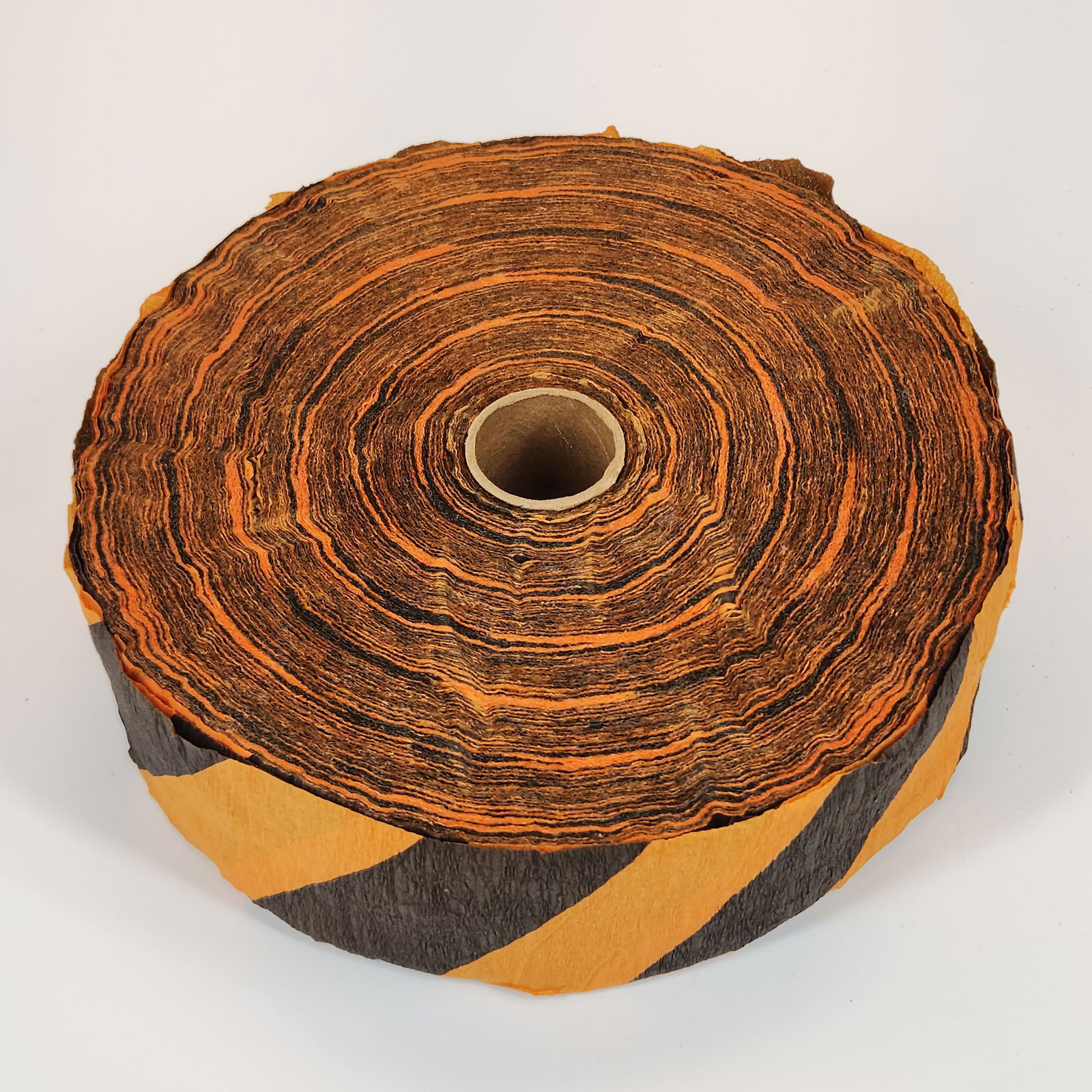 ROLL OF HALLOWEEN CREPE PAPER: REMAINS IN GOOD CONDITION. MEASURES APPROXIMATELY 6" ACROSS BY 2" TALL.