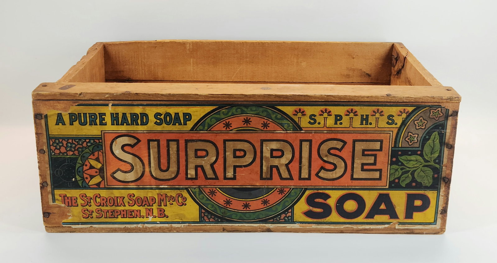 SURPRISE SOAP ADVERTISING WOOD BOX W/ LABEL: REMAINS IN FAIR TO GOOD CONDITION, SHOWING SOME TYPICAL WEAR. MISSING LID AND WEAR TO LABEL. MEASURES APPROXIMATELY 21" ACROSS.