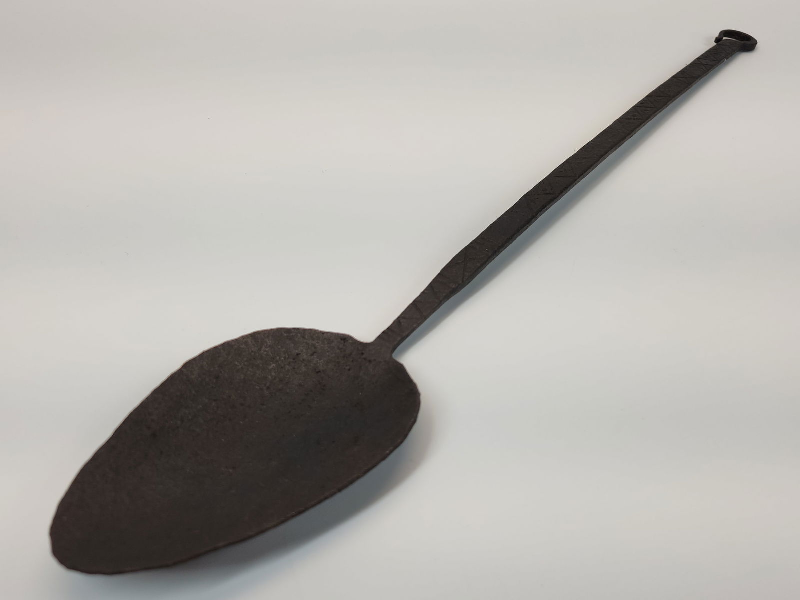 ANTIQUE HAND WROUGHT IRON HEARTH LADLE: REMAINS IN GOOD CONDITION, SHOWING TYPICAL WEAR. INSCRIBED HANDLE MEASURING 20" LONG.