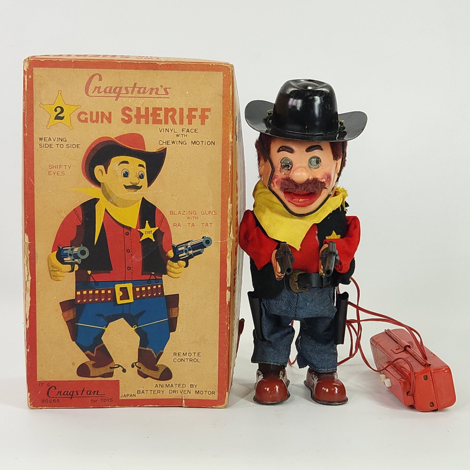 CRAGSTAN BATTERY OP 2 GUN SHERIFF W/ BOX: REMAINS IN GOOD CONDITION, SHOWING SOME TYPICAL WEAR. HAS ISSUE WITH ONE EYE AND LEFT SIDE OF FACE. BOX IN FAIR CONDITION, SHOWING WEAR. UNTESTED.