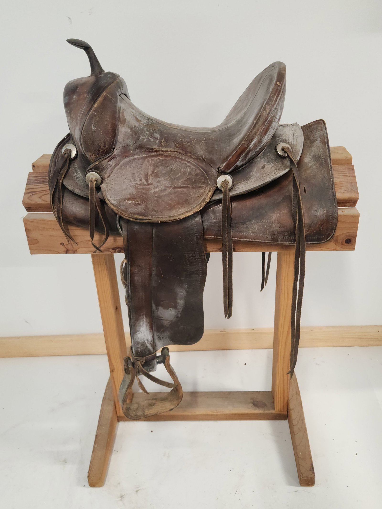 LEATHER SADDLE WITH WOODEN STIRRUPS: LEATHER SHOWS WEAR AND DISCOLORATION