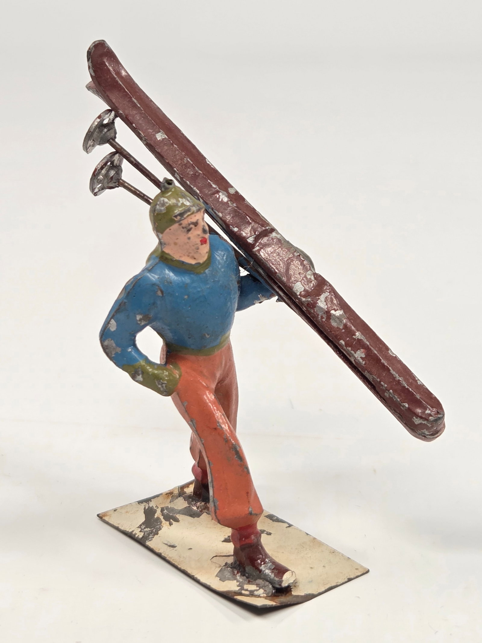 ANTIQUE HAND PAINTED LEAD MAN CARRYING SKIS: REMAINS IN FAIR TO GOOD CONDITION, SHOWING SOME PAINT WEAR.