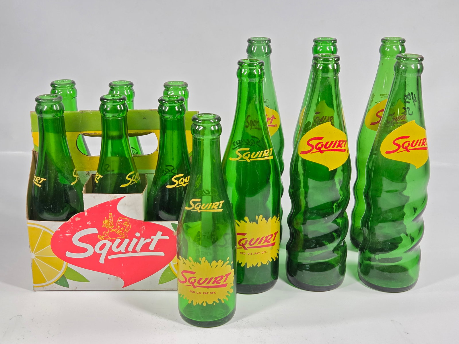 13) SQUIRT SODA GREEN GLASS BOTTLES & CARRIER: BOTTLES ALL REMAIN IN GOOD CLEAN CONDITION. CARRIER REMAINS NICE, SHOWING SOME WEAR.