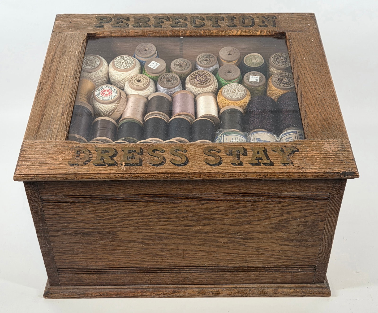 PERFECTION DRESS STAY COUNTRY STORE CABINET: REMAINS IN GOOD CONDITION, SHOWING SOME TYPICAL WEAR. ORIGINAL LABEL SHOWS LOSS. INCLUDES SPOOLS OF THREAD AS SHOWN.