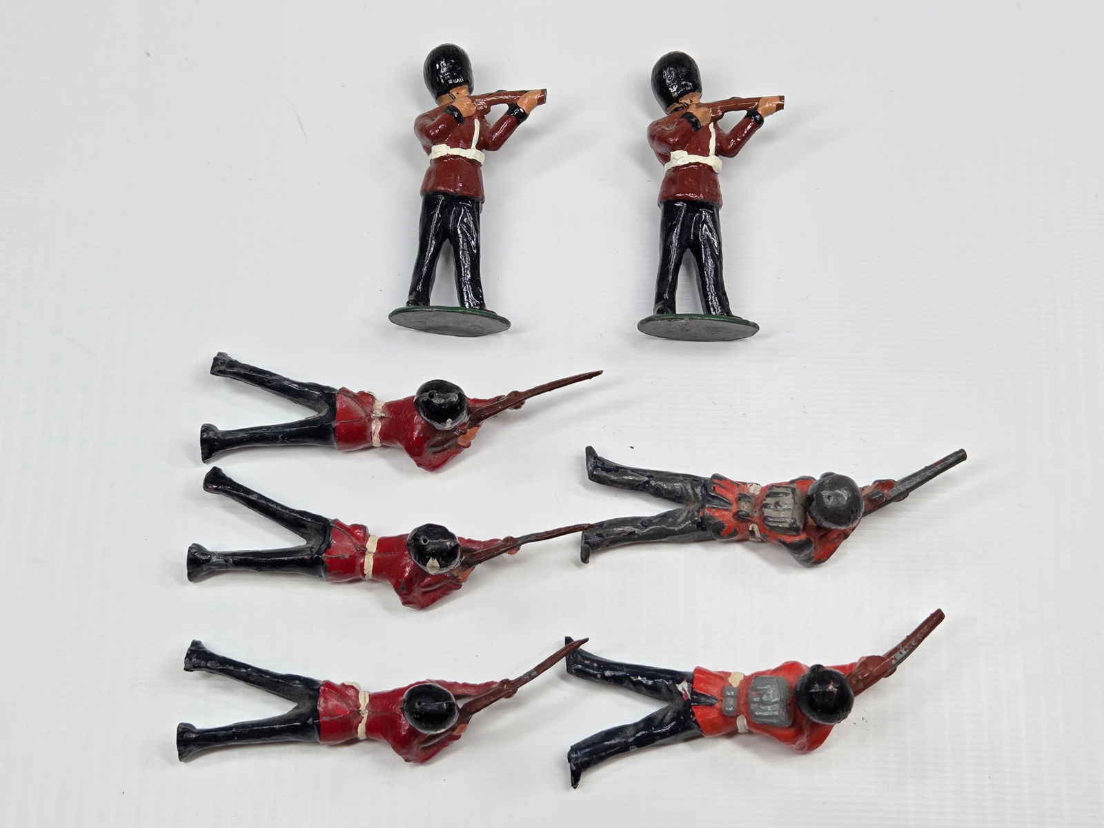 7) VINTAGE BRITAIN REDCOAT SOLDIERS: ALL REMAIN IN FAIR TO GOOD CONDITION, SHOWING SOME PAINT WEAR. 4 WITH RIFLE TIPS BROKEN.