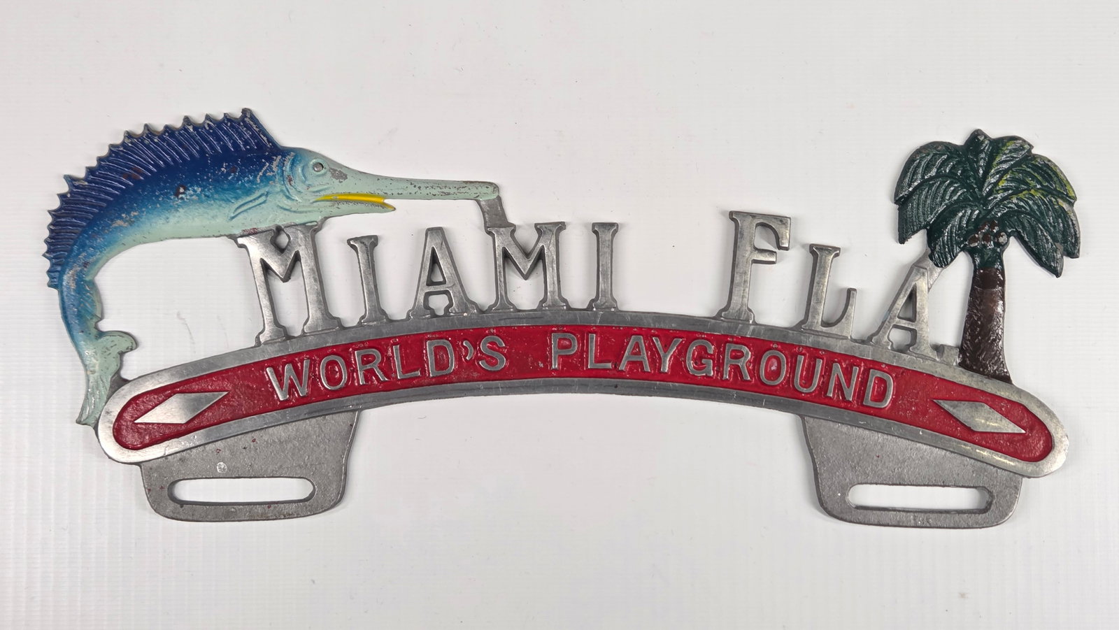MIAMI FLORIDA LICENSE PLATE TOPPER: REMAINS IN GOOD CONDITION, SHOWING SOME LIGHT PAINT WEAR.