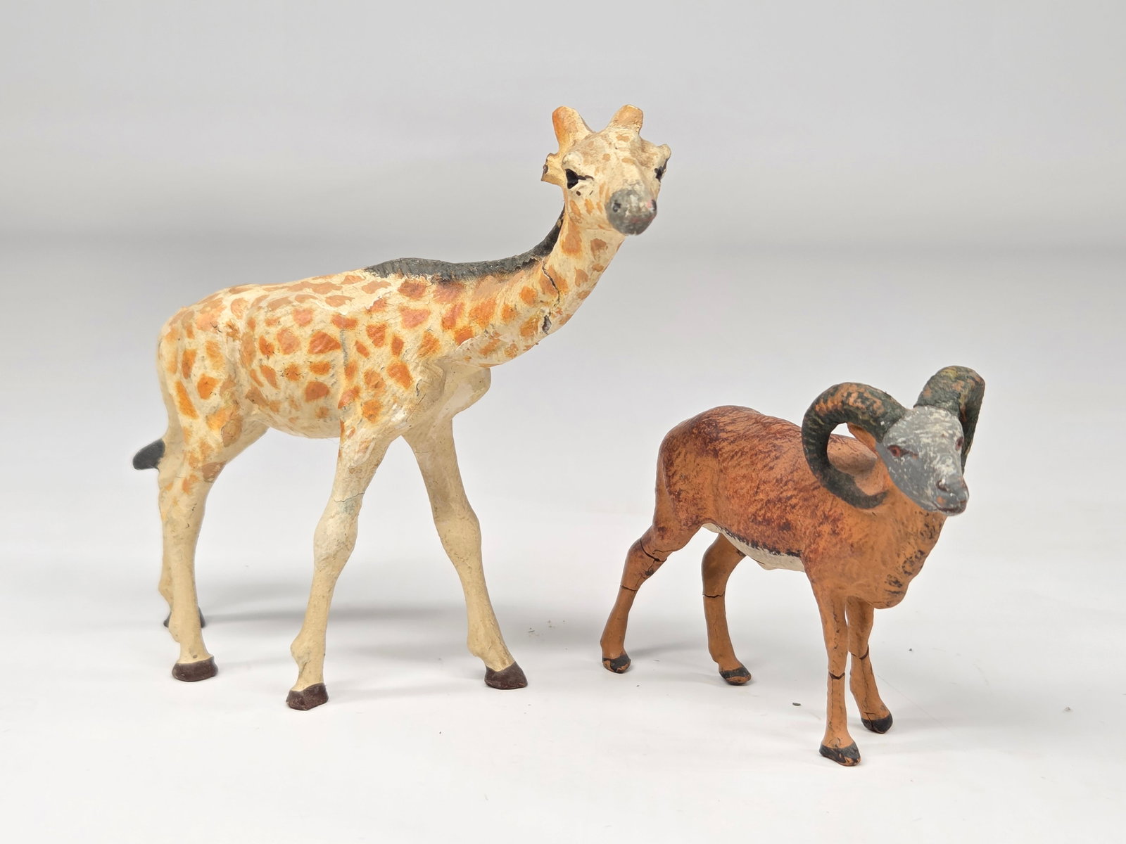 ANTIQUE GERMAN COMPOSITION GIRAFFE & RAM: BOTH REMAIN IN FAIR CONDITION, SHOWING SOME WEAR. BOTH WITH CRACKING. GIRAFFE WITH BROKEN EARS.