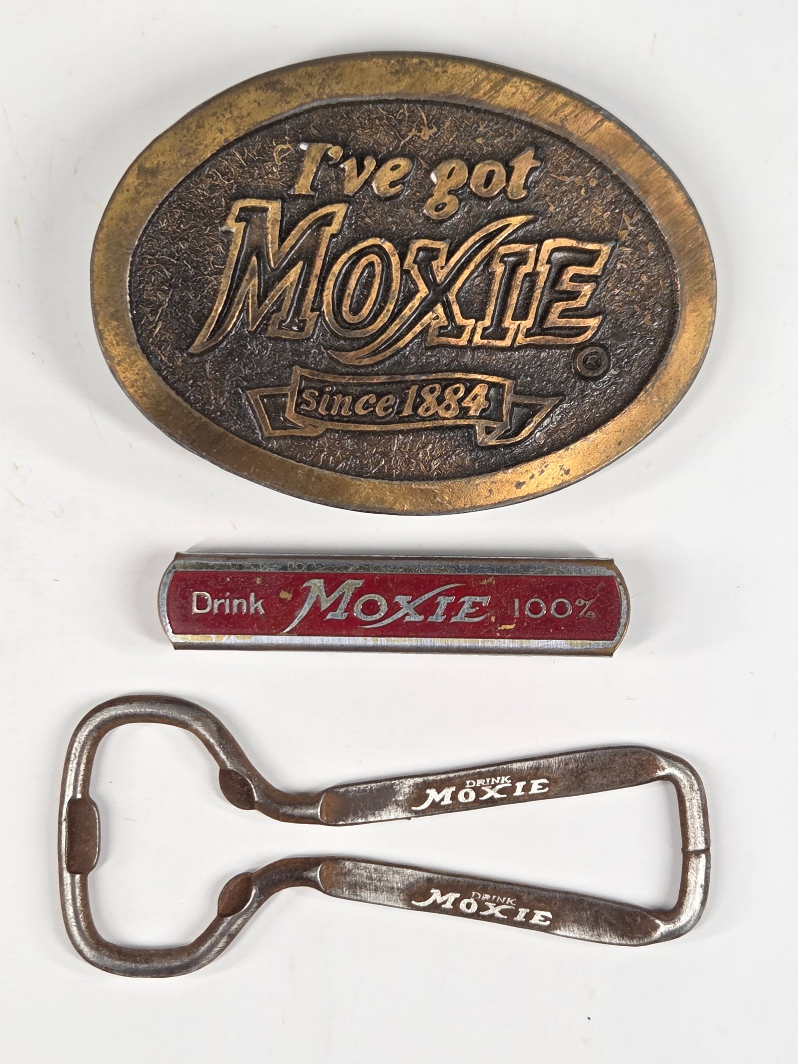 MOXIE BELT BUCKLE & 2) BOTTLE OPENERS: ALL REMAIN IN GOOD CONDITION, SHOWING SOME TYPICAL WEAR.