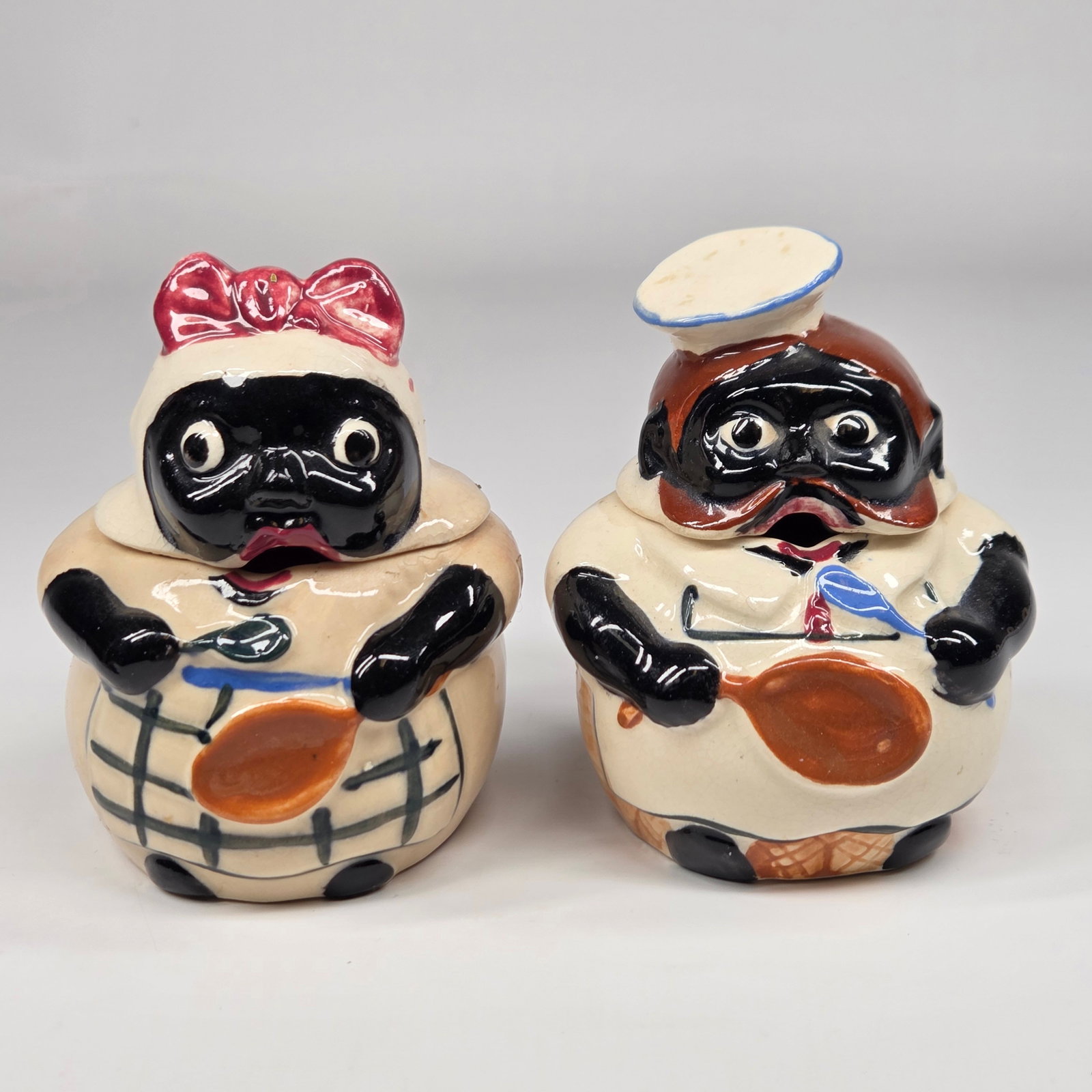 PAIR OF VINTAGE CERAMIC BLACK AMERICANA JARS: BOTH REMAIN IN GOOD CONDITION, SHOWING SOME TYPICAL WEAR. BOTH WITH SOME CRAZING.