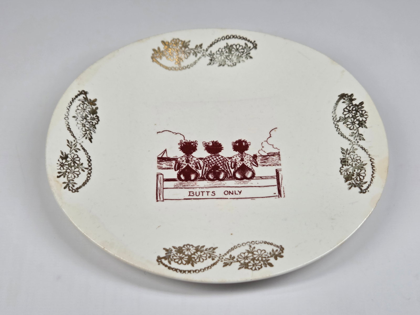 ANTIQUE BLACK AMERICANA BUTTS ONLY PLATE: REMAINS IN FAIR CONDITION, SHOWING A FEW CHIPS.