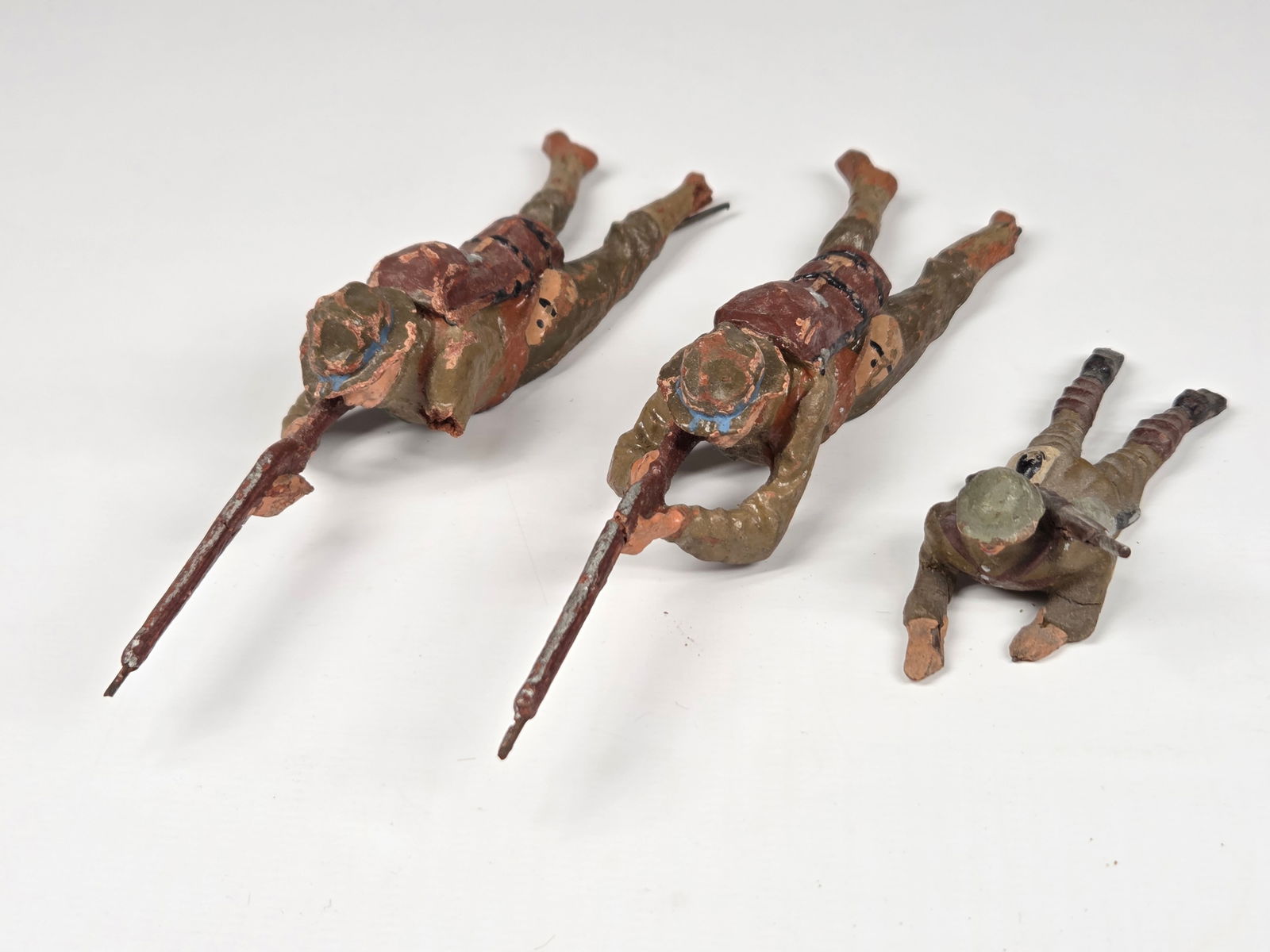 3) GERMAN ELASTOLIN SOLDIERS W/ RIFLES: SMALL SOLDIER REMAINS IN FAIR CONDITION, SHOWING SOME TYPICAL WEAR. BOTH LARGER SOLDIERS SHOWING WEAR. ONE WITH BROKEN / MISSING ARM AND FOOT. THE OTHER WITH BROKEN / MISSING FOOT AND BREAK IN RIFLE.