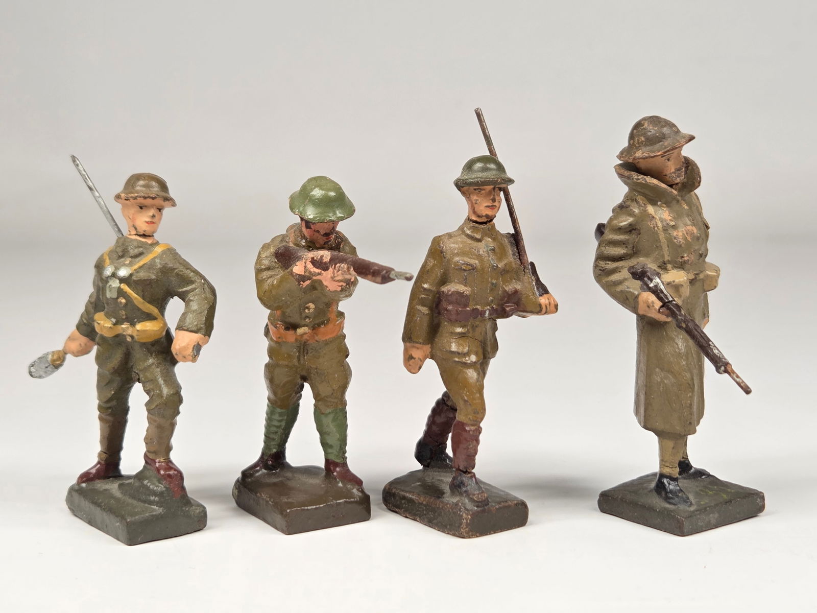 4) GERMAN LINEOL COMPOSITION SOLDIERS W/ RIFLES: ALL REMAIN IN FAIR CONDITION, SHOWING SOME TYPICAL WEAR. ALL HAVE CRACK ON RIFLE.