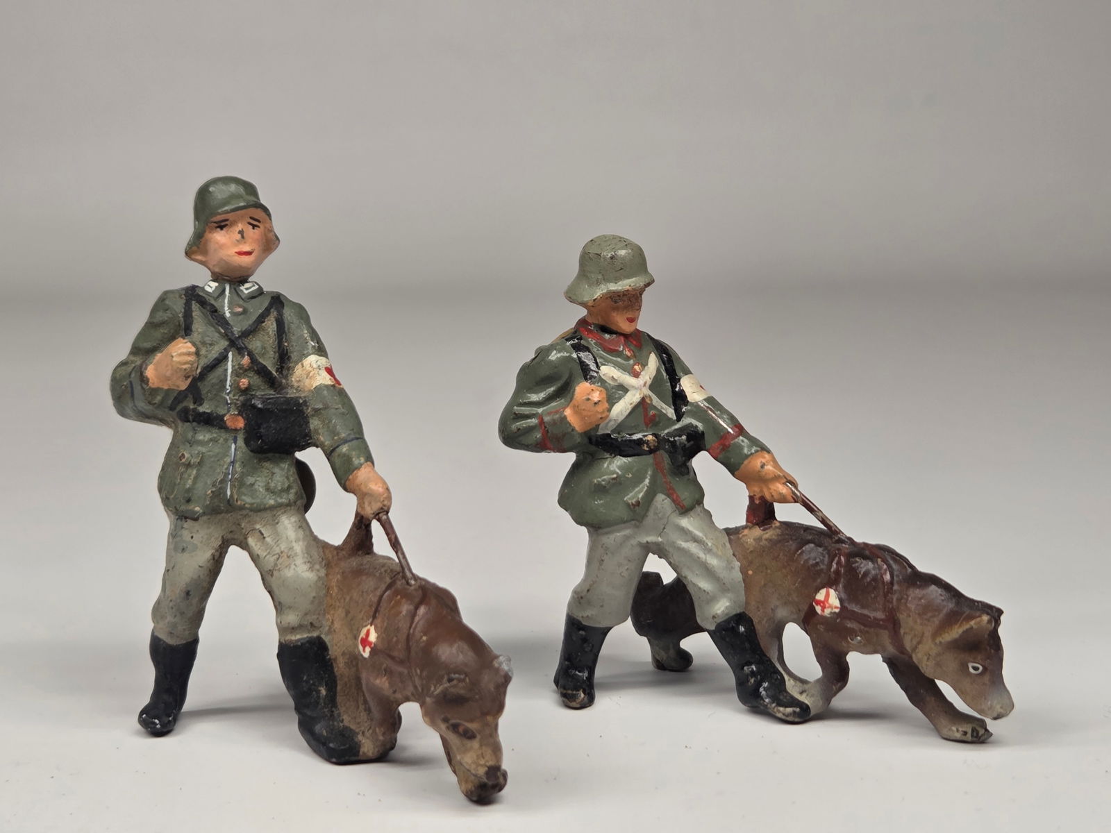 2) GERMAN COMPOSITION SOLDIERS W/ DOGS: BOTH REMAIN IN FAIR TO GOOD CONDITION, SHOWING SOME TYPICAL WEAR.