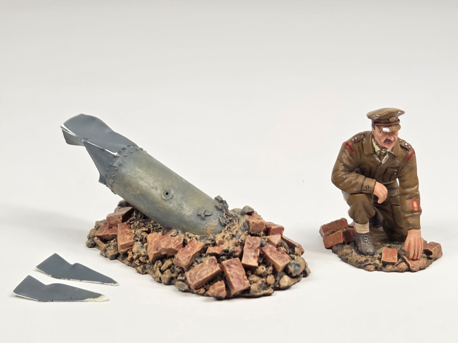 KING & COUNTRY FIELDS OF BATTLE BOMB & SOLDIER: BOTH REMAIN IN FAIR CONDITION, SHOWING WEAR. BOMB WITH TWO BROKEN FINS AND SOLDIER WITH CHIP ON HAT BRIM.